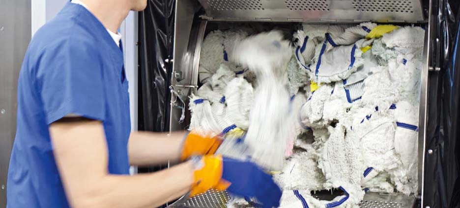 jemand räumt weiße Wischbezüge aus eine großen Waschmaschinentrommel